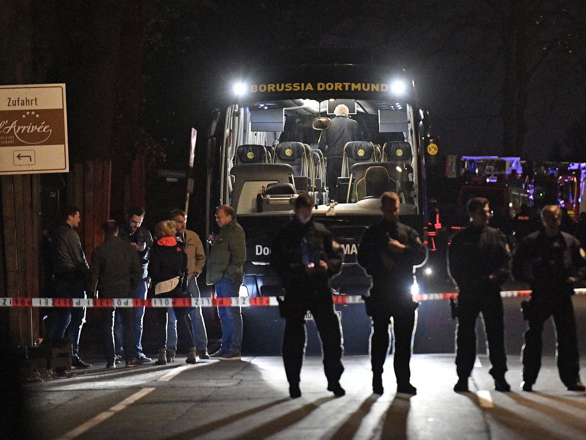 Policajti stoja pred poškodeným autobusom Borussie Dortmund