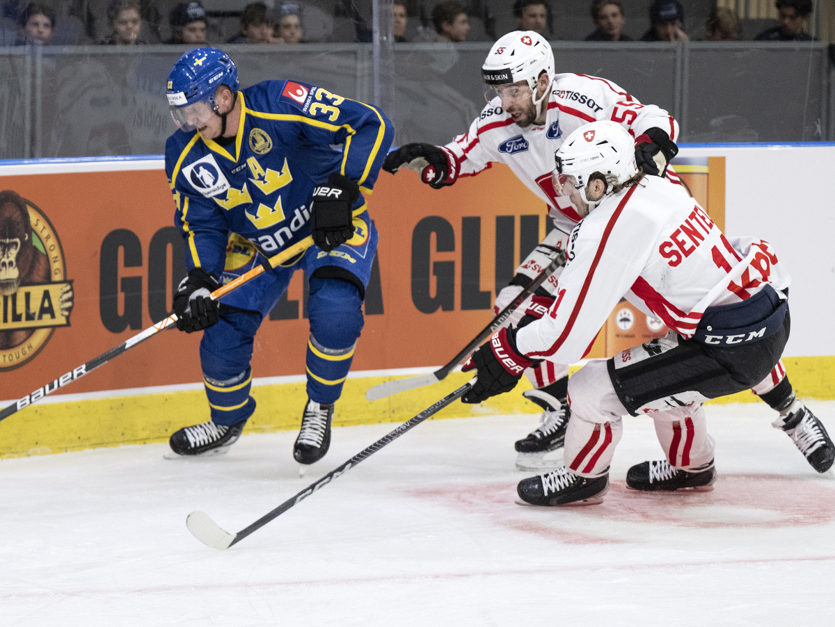 Švéd Jakob Silfverberg čelá náporu švajčiarskej dvojice Sven Senteler a Romain Loeffel v zápase Euro Hockey Tour pred MS 2023 v hokeji.