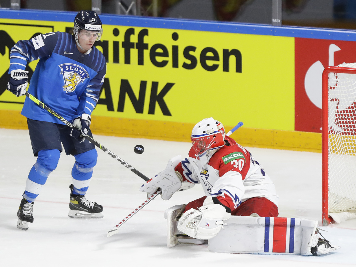 Fínsky hokejista Jere Innala (vľavo) strieľa gól českému brankárovi Šimonovi Hrubecovi