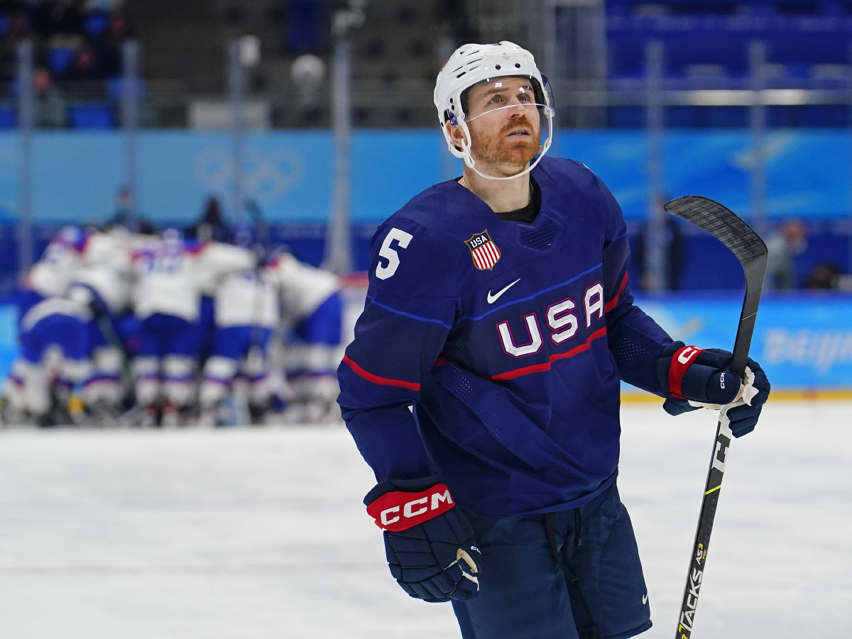 Smutný hráč USA David Warsofsky, v pozadí radosť slovenských hokejistov
