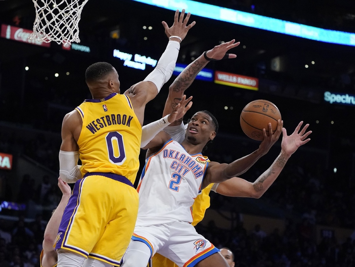 Hráč Oklahoma City Thunder  Shai Gilgeous-Alexander (vpravo) strieľa na kôš cez Russella Westbrooka z Los Angeles Lakers