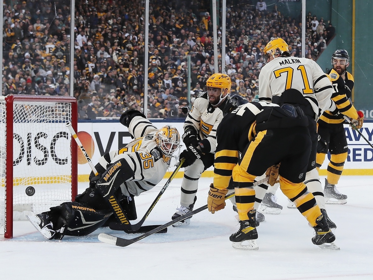 Brankár Tristan Jarry (35) z Pittsburghu Penguins vyráža puk pred hráčom Bostonu Jakeom DeBruskom počas zápasu pod holým nebom NHL Winter Classic Boston Bruins - Pittsburgh Penguins v bostonskom Fenway Parku