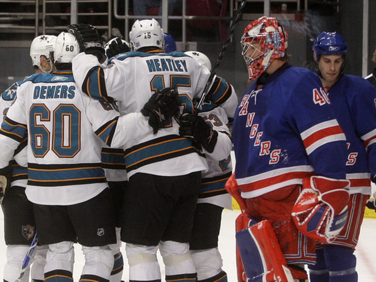 Gólman Rangers Steve Valiquette a tešiaci sa hráči Sharks