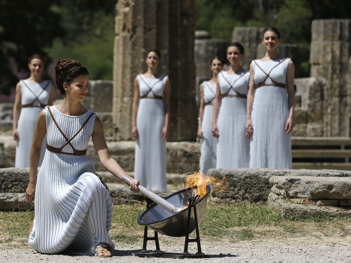Herečka Katerina Lehou v kostýme veľkňažky zapaľuje pochodeň od olympijského ohňa počas zapálenia olympijského ohňa v starobylej Olympii
