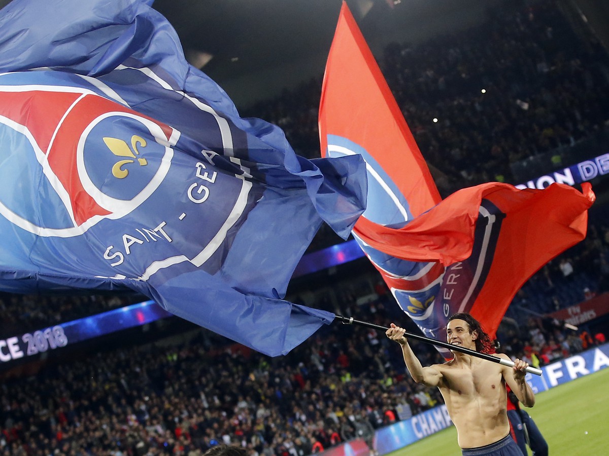 Futbalista Paríža Saint-Germain Edinson Cavani máva klubovou vlajkou a teší sa zo zisku majstrovského titulu