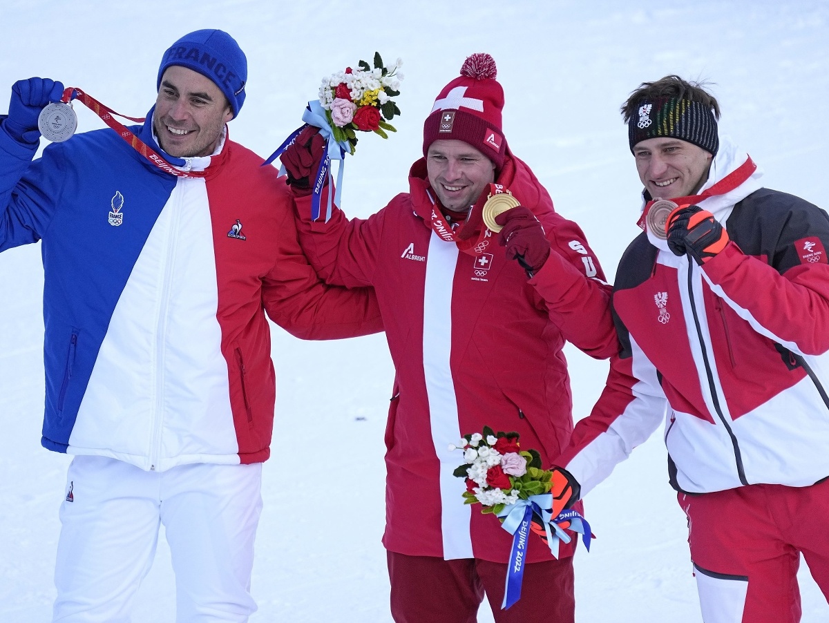 Švajčiarsky alpský lyžiar Beat Feuz (uprostred) pózuje so zlatou olympijskou medailou, ktorú získal v zjazde. Druhý skončil 41-ročný Francúz Johan Clarey (vľavo), tretí bol Rakúšan Matthias Mayer (vpravo). FOTO TASR/AP 