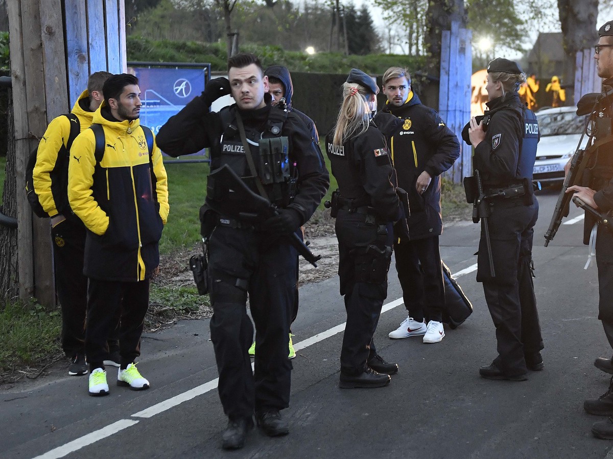 Hráč Dortmundu Marcel Schmelzer sa rozpráva s príslušníkmi polície neďaleko poškodeného autobusu po bombovom útoku v Dortmunde