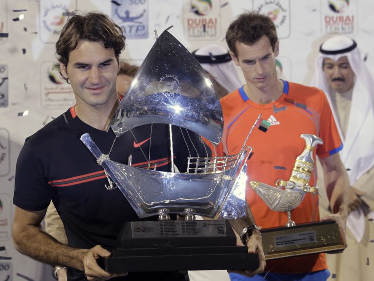 Roger Federer s trofejou, v pozadí Murray