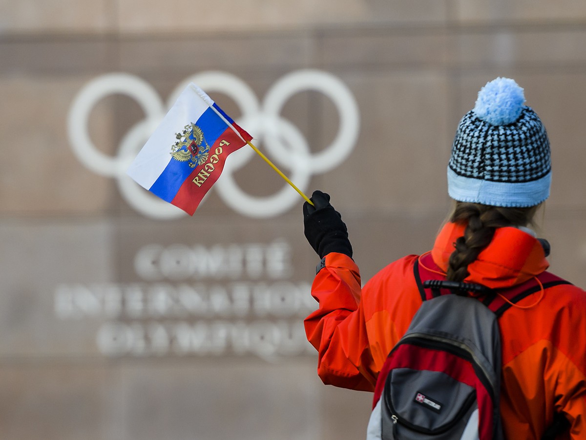 Žena drží ruskú zástavu pred vstupom do sídla Medzinárodného olympijského výboru