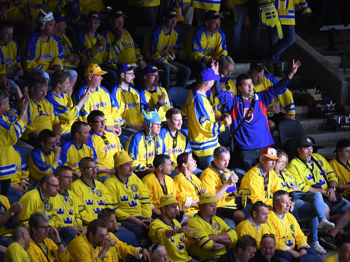 Slovenský fanúšik sa teší medzi švédskymi fanúšikmi po strelení vyrovnávajúceho gólu na 3:3
