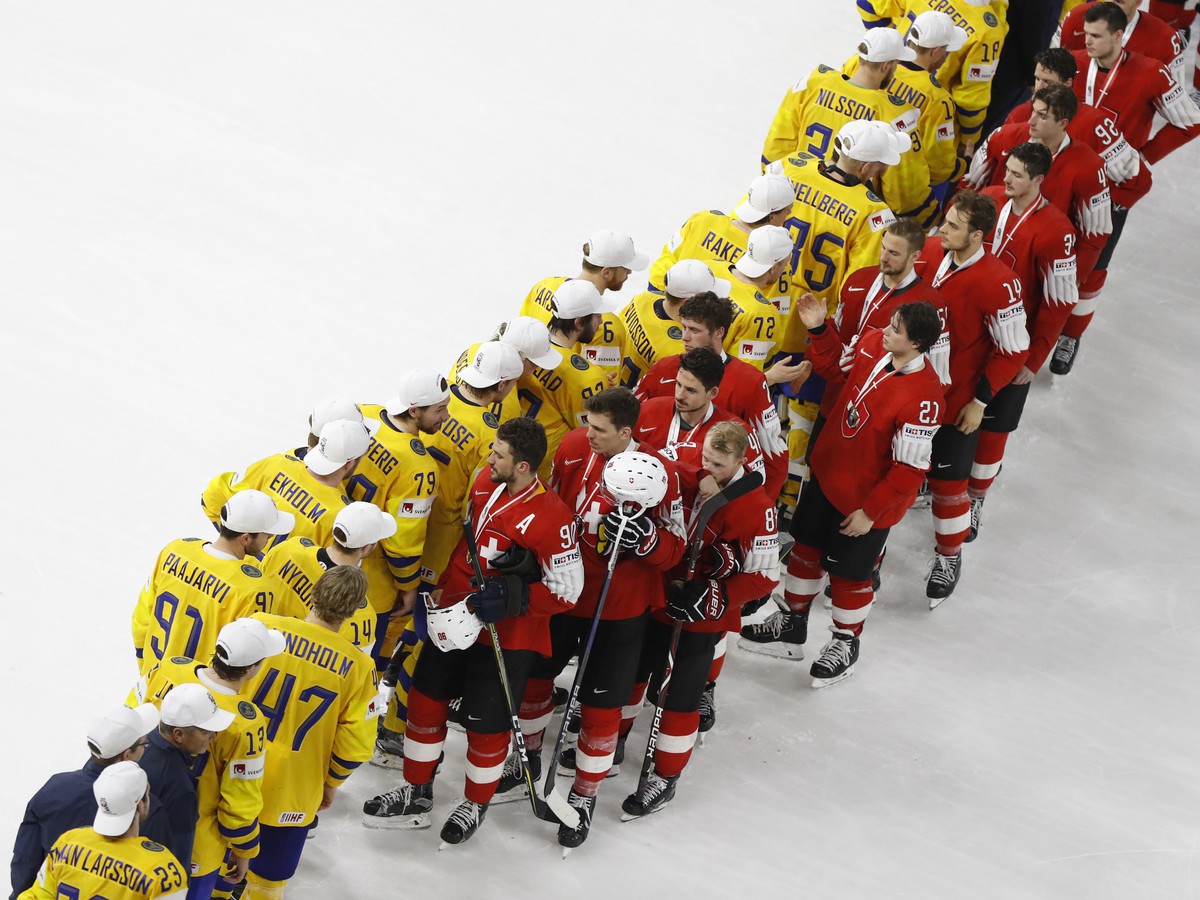 Švédski hokejisti (vľavo) si podávajú ruky so švajčiarskymi hokejistami po finále