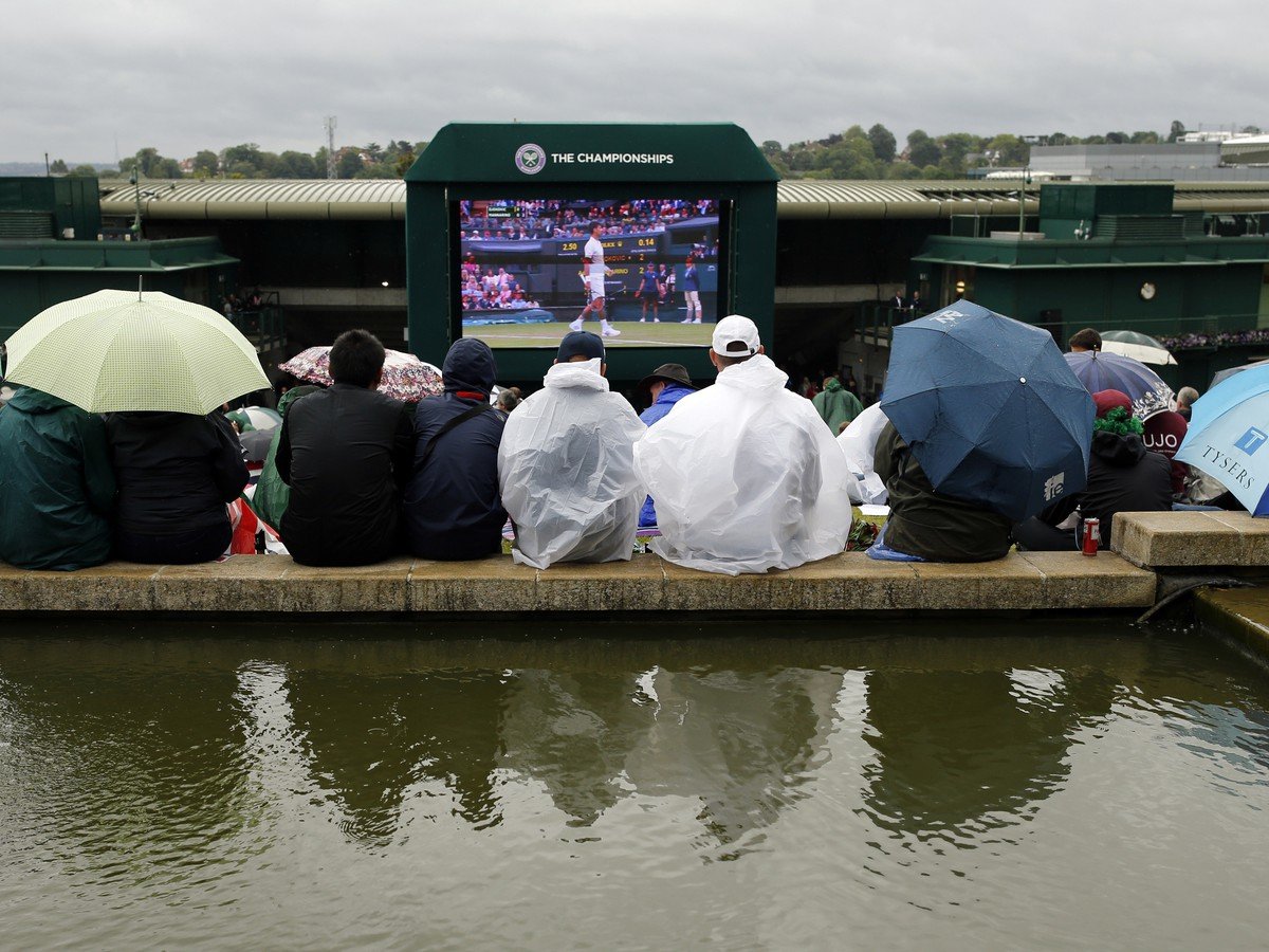 Diváci na Wimbledone sledujú zápas pod dáždnikmi