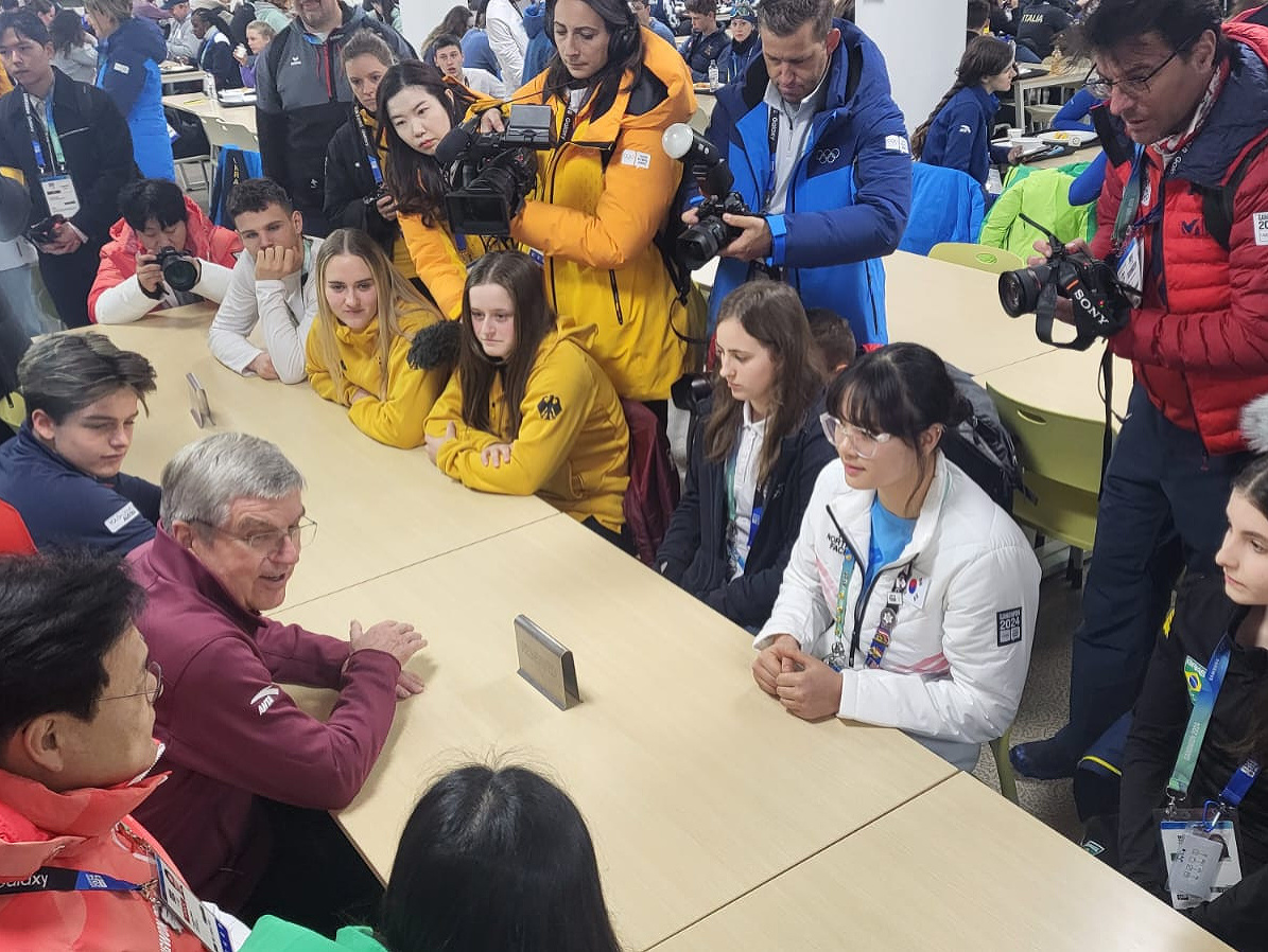 Thomas Bach počas debaty so športovcami v jedálni olympijskej dediny mládeže, Viktória Praxová v strede medzi športovkyňami z Nemecka a Kórejskej republiky.