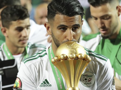 Na snímke kapitán alžírskej futbalovej reprezentácie Riyad Mahrez bozkáva pohárovú trofej víťaza Afrického pohára národov 