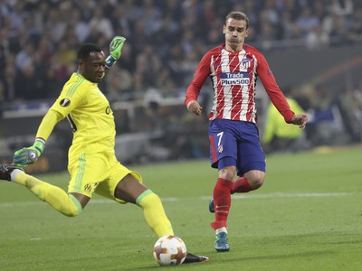 Brankár Marseille Steve Mandanda (vľavo) odkopáva loptu vedľa Antoineho Griezmanna z Atlético