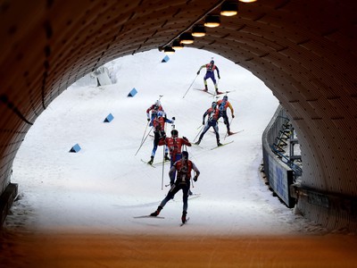 Biatlonisti prechádzajú tunelom počas pretekov mužských štafiet