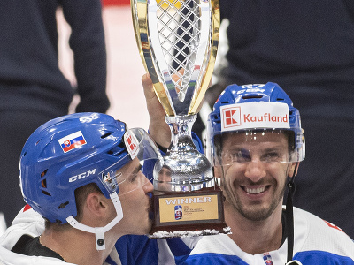 Slovenskí hokejisti zľava Adam Ružička a kapitán Marek Hrivík držia trofej po postupe na zimné olympijské hry 2022 do Pekingu