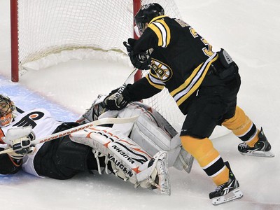 Patrice Bergeron sa pokúša pretlačiť puk za chrbát Briana Bouchera