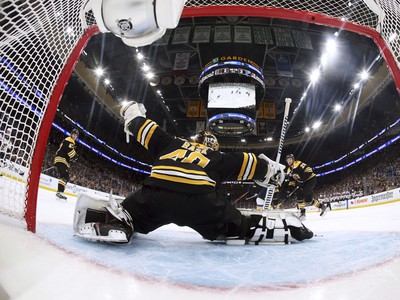 Puk letí za chrbát brankára Bostonu Bruins Tuukku Raska