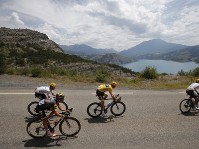 Brit Chris Froome v žltom drese lídra prechádza v pelotóne okolo jazera Serre-Poncon počas 19. etapy cyklistických pretekov Tour de France