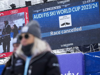 Diváci stoja pri obrazovke, na ktorej je oznam o zrušení pretekov zjazdu Svetového pohára alpských lyžiarov v americkom stredisku Beaver Creek