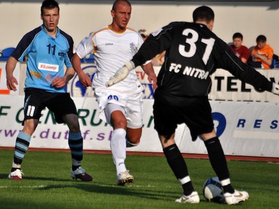 Brankár FC Nitra Lukáš Hroššo (vpravo) odkopáva loptu pred hráčom MFK Dubnica nad Váhom Michalom Filom (uprostred) a svojim spoluhráčom Lukášom Štetinom