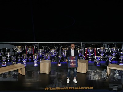 Lúčiaci sa Andrés Iniesta s dresom FC Barcelona v obklopení trofejí