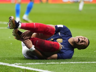 Francúzsky futbalista Kylian Mbappé leží na zemi po faule
