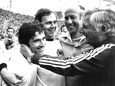 Na archívnej snímke zo 7. júla 1974 futbalista Nemeckej spolkovej republiky Gerd Müller (vľavo), tréner Helmut Schön (druhý sprava), jeho asistent Jupp Derwall (vpravo) a kapitán Franz Beckenbauer (druhý zľava) sa tešia po výhre 2:1 nad Holandskom vo finále majstrovstiev sveta vo futbale v Berlíne.