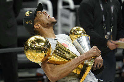 Útočník Giannis Antetokounmpo z Milwaukee Bucks pózuje s cenou pre najužitočnejšieho hráča finále (MVP) a trofejou pre šampióna NBA