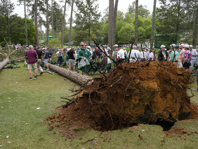 Organizátori odvádzajú  návštevníkov od borovíc, ktoré spadli v blízkosti 17. jamky vplyvom silného vetra počas 2. kola golfového major turnaja Masters v Auguste