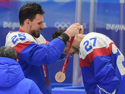 Na snímke vľavo Peter Zuzin dáva bronzovú medailu kapitánovi Marekovi Hrivíkovi, slovenskí hráči oslavujú po zisku bronzu po zápase olympijského turnaja v hokeji mužov o bronz Slovensko - Švédsko na ZOH 2022 v Pekingu 