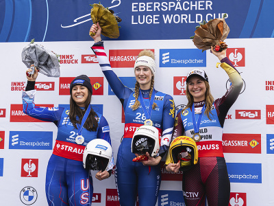 Rakúšanka Madeleine Egleová oslavuje na pódiu víťazstvo v pretekoch Svetového pohára v sánkovaní v Innsbrucku 3. decembra 2022. Vľavo druhá  Američanka Emily Sweeneyová, vpravo tretia Nemka Julia Taubitzová.