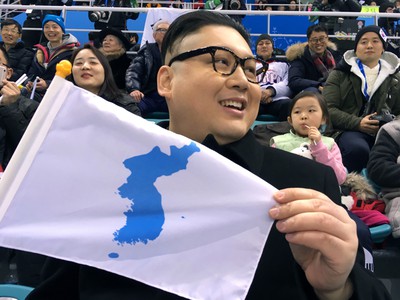 Howard z Austrálie, imitátor severokórejského lídra Kim Čong-una drží vlajku  zjednotenej výpravy uporiadateľskej Kórejskej republiky a KĽDR počas zápasu hokejového turnaja žien Kórea - Japonsko