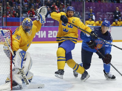 Švéd Niklas Kronwall (v strede) v súboji s Fínom Laurim Korpikoskim (vpravo). Sleduje brankár Henrik Lundqvist