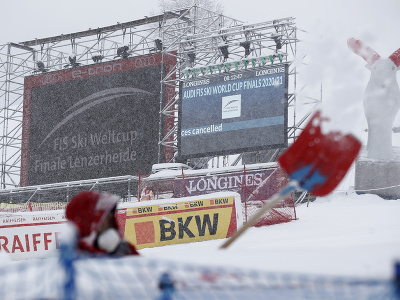 Muž odhrabáva sneh v cieli po zrušení zjazdu žien a mužov Svetového pohára 17. marca 2021 vo švajčiarskom Lenzerheide