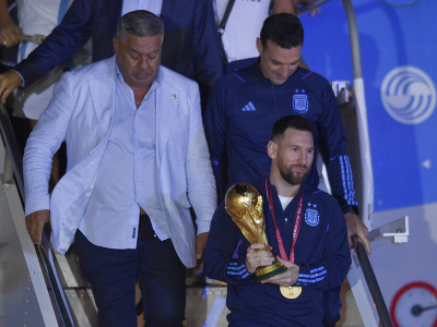 Argentínsky futbalista Lionel Messi drží trofej pre víťaza MS vo futbale počas vystupovania z lietadla 20. decembra 2022 v Buenos Aires