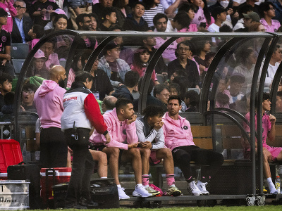 Hviezdny futbalista Interu Miami Lionel Messi (druhý sprava) sedí na lavičke počas priateľského zápasu proti domácemu  výberu na  štadióne v Hongkongu