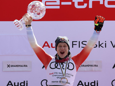 Švajčiarsky lyžiar Marco Odermatt oslavuje na pódiu s veľkým glóbusom za celkové prvenstvo vo Svetovom pohári