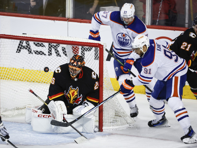 Evander Kane (Edmonton) sa snaží prestrčiť puk za chrbát brankára Calgary