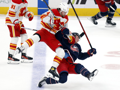 Hokejista Calgary Flames  Rasmus Andersson (uprostred) a hráč Columbusu Blue Jackets Patrik Laine počas zrážky