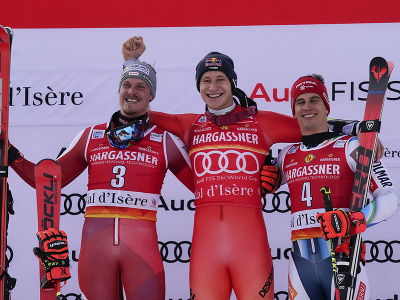 Švajčiarsky lyžiar Marco Odermatt (uprostred) oslavuje na pódiu s druhým Rakúšanom Manuelom Fellerom (vľavo) a tretím Slovincom Žanom Kranjecom (vpravo) po pretekoch 2. kola obrovského slalomu mužov Svetového pohára v alpskom lyžovaní vo francúzskom Val D'Isere