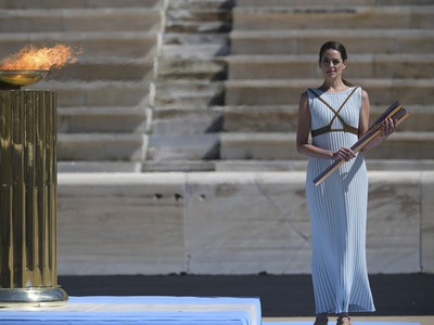 Grécka herečka Xanthi Georgiou v odeve starogréckej kňažky stojí s pochodňou pri oltári s olympijským ohňom počas rituálu jeho slávnostného odovzdania pre letné olympijské hry 2020 v Tokiu