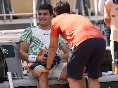 Španielsky tenista Carlos Alcaraz dostáva ošetrenie po tom, ako dostal kŕč do nohy v zápase proti Srbovi Novakovi Djokovičovi