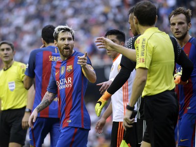 Futbalista FC Barcelona Lionel Messi sa rozpráva s rozhodcom po tom, čo diváci začali hádzať predmety do futbalistov Barcelony
