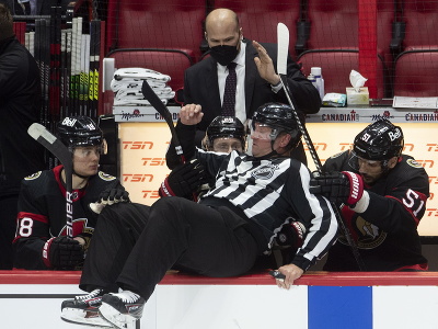 Hráči Ottawy Senators pomáhajú čiarovému rozhodcovi Derekovi Nansenovi po tom, ako sa prepadol na striedačku