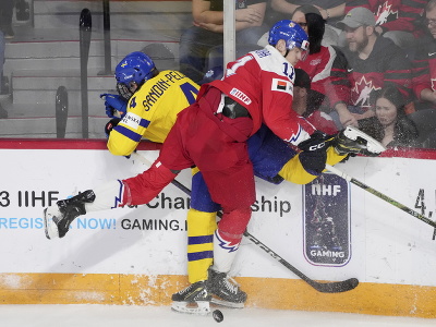 Švédska hokejista Axel Sandin-Pellikka (vľavo) a hráč Česka Adam Měchura bojujú o puk pri mantineli