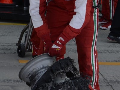 Mechanik drží koleso s roztrhanou pneumatikou Felippeho Massu