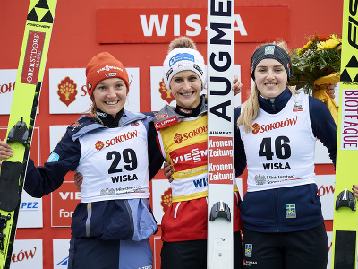 Rakúska skokanka na lyžiach Eva Pinkelnigová (uprostred) sa teší po triumfe na druhom podujatí Svetového pohára v poľskej Wisle v nedeľu 6. novembra 2022. Druhá skončila Katharina Althausová (vľavo) z Nemecka a tretia bola Švédka Frida Westmanová (vpravo).