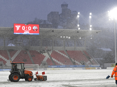 Traktor odhŕňa sneh z hracej plochy po tom, čo hlavný rozhodca v 20. minúte prerušil zápas pre nespôsobilý terén 
